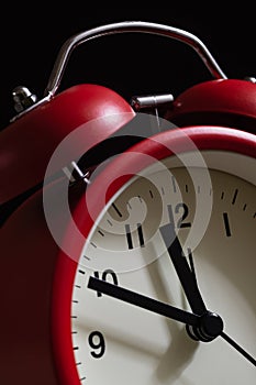 Red alarm clock close up. It's showing ten minutes to twelve o'c photo