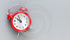 Red alarm clock on a grey background