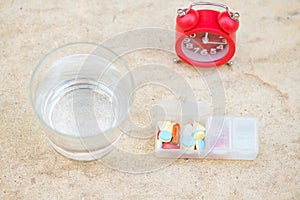 Red alarm clock,daily pill box and glass of water