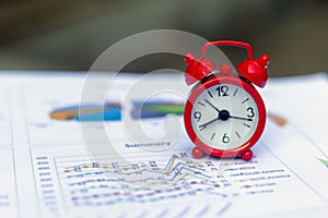 The red alarm clock rests on a graph of important time every second. Concepts for business deadlines, schedules and urgency.