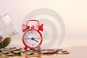 Red alarm clock on stack of coins in concept of savings and money growing or energy save. Business investment growth concept.