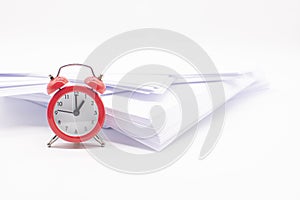 A red alarm clock and a stack of white office paper on the desktop. Business concept