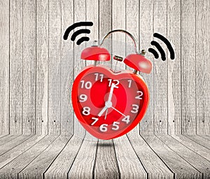 Red alarm clock waking up on wooden