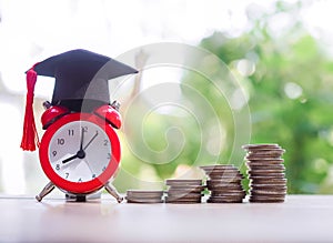 Red alarm with graduation hat and stack of coins, The concept of saving money for education, student loan, scholarship, tuition