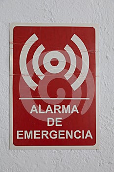 Red alarma de emergencia - emergency alarm - sign on the white wall under the lights photo