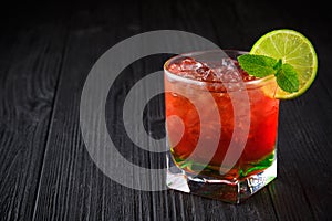 Red alcohol cocktail with mint and lime on black background