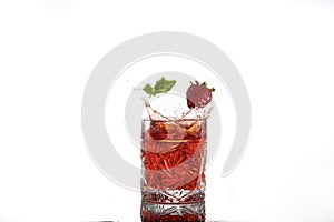 Red alcohol cocktail with splash, strawberry and mint leaf isolated on white