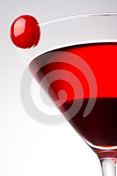 A red alcoholic cocktail with a cherry on the glass isolated on a white background