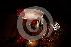 A red alcoholic cocktail with foam in a glass stands on the bar