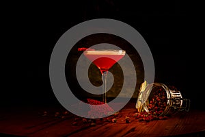 A red alcoholic cocktail with foam in a glass stands on the bar