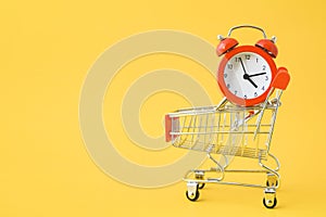Red analog clock on shopping cart with yellow background , payday ,shopping day or sale promotion