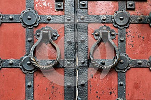 Red ancient gates with the metal fittings and the round doorknobs
