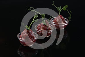 Red appetizing Tartar sauce in three pialas, decorated with a stem of sprouted green peas, close-up