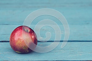 A red apple on a blue wooden table.