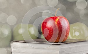 Red apple and book on a table.