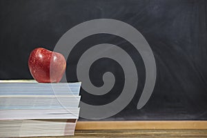 Red apple and books  on wooden table and blackdoard background.school for kids
