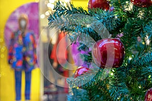 Red apple on the Christmas tree against the backdrop of a showcase with mannequins.