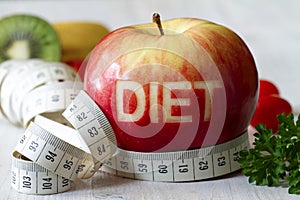 Red apple with cut-out word diet, measuring tape and fruits, diet and healthy lifestyle concept