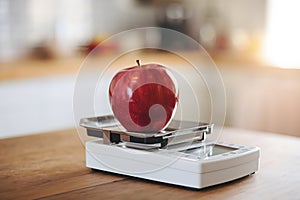 Red apple on a digital scale with warm kitchen lighting highlighting freshness