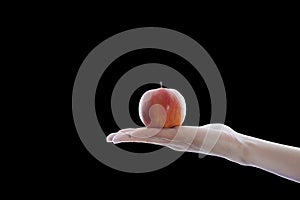 Red apple on female hand isolated on black background