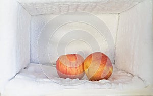 Red apple in freezer of a refrigerator. Ice buildup inside of a