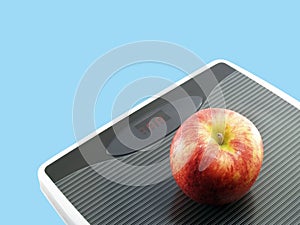 red apple on grey digital weight scale isolated on blue background