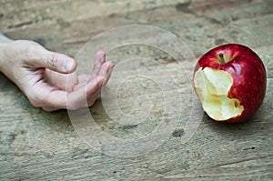 Red apple and hand on wooden table background