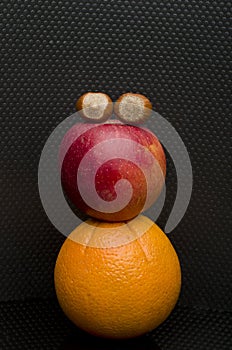 Red apple, hazelnut and an orange isolated on black.