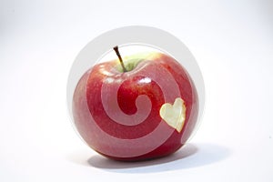 Red apple on a white background, with a cut out heart on its side