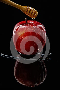 Red apple with honey on black