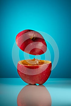 Red apple with juice on a blue background