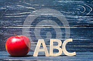 Red apple and letters ABC on a dark background of a school board
