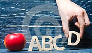 Red apple and letters ABCD. The hand puts the letter D in the al