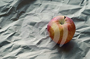 Red apple lies on crumpled wrapping paper