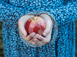A red apple in a little girl`s hands