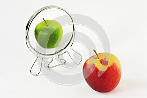 Red apple looking in the mirror and seeing itself as a green apple - Concept of daltonism and color blindness photo