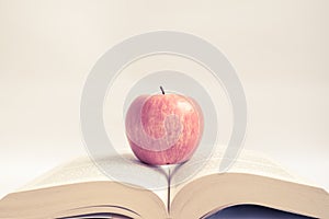 Red apple on an open book in vintage tone