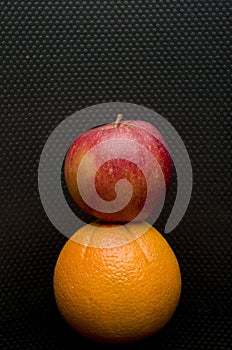 Red apple and an orange isolated on black.
