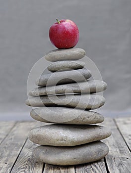 Red apple on a pebble pyramid. At the pinnacle of balance
