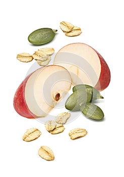 Red apple pieces, green pumpkin seeds and rolled oats isolated on white background. Falling mix