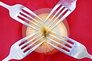 Red apple on red with four forks