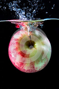 Red apple spash in water on black