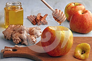 Red apple and spoon with dripping honey on background of ingredients on blue wooden table. Cooking baked apples with