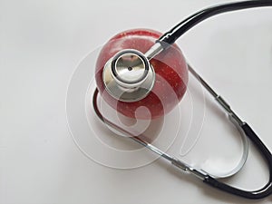 Red apple, with a stethoscope, on a white background, top view, focus on the foreground. photo