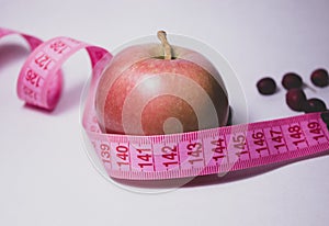 A red apple with a tape measure around it. Side view. Diet concept.