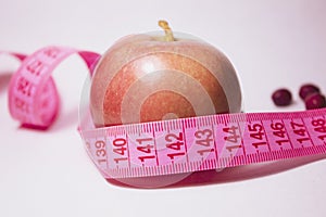 A red apple with a tape measure around it. Side view. Diet concept.