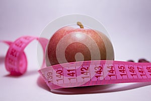 A red apple with a tape measure around it. Side view. Diet concept.