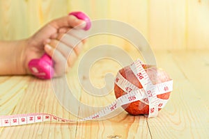 Red apple with Tape Measure and background hand holding Dumbell