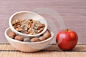 Red apple and walnuts on wooden dishes