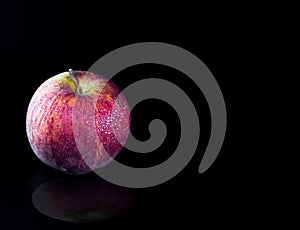 Red apple with water droplet on glossy surface
